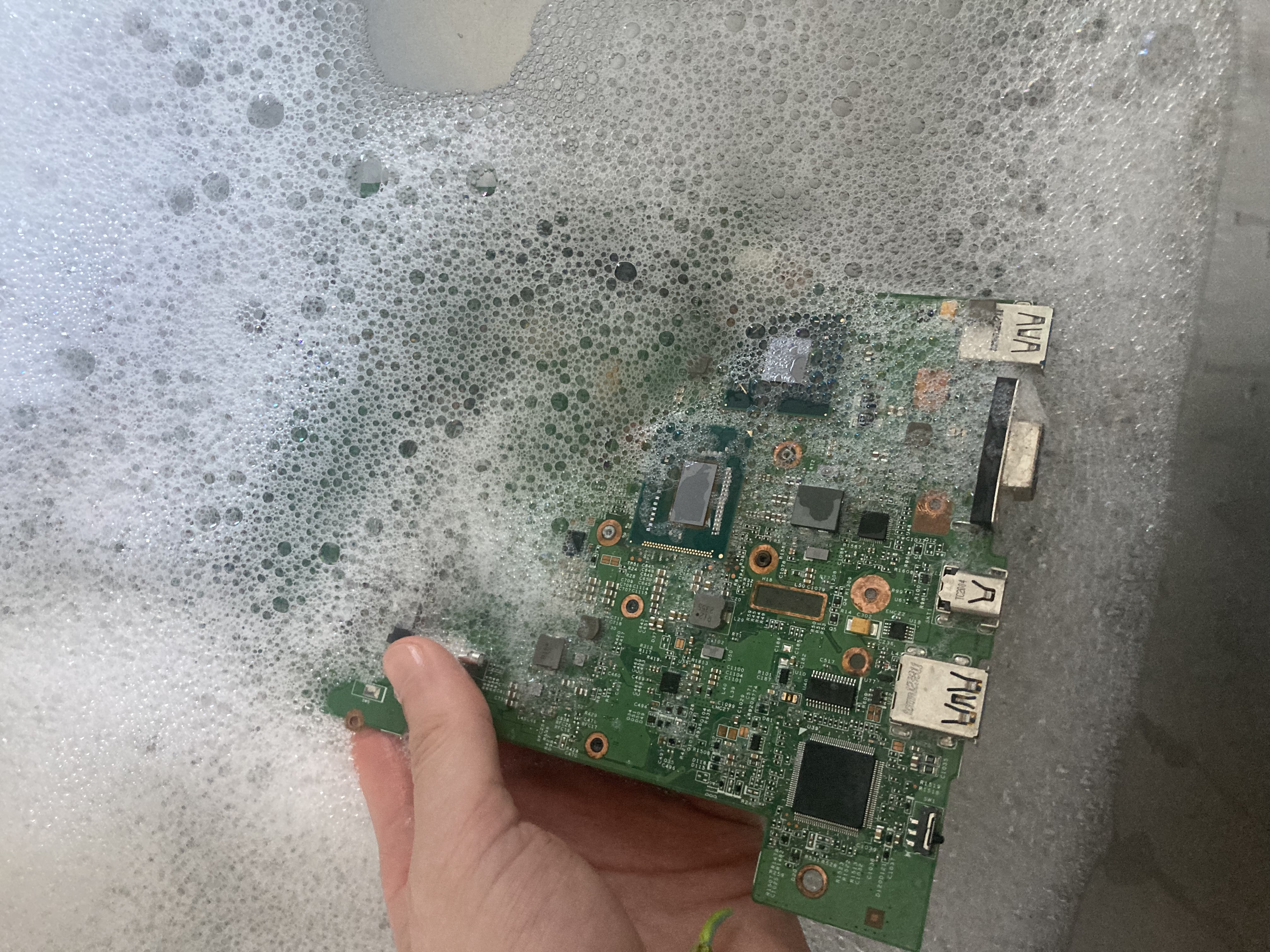 The mainboard of the thinkpad
x230 being dipped into a sink filled with soapy water